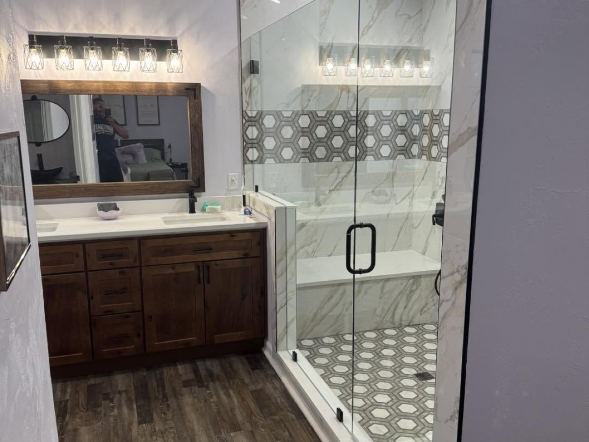 Bathroom with a dark wood vanity, plank floor and a glass-enclosed tile shower