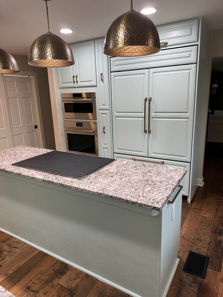 Remodeled kitchen with a granite-topped island, white cabinets, and pendant lights