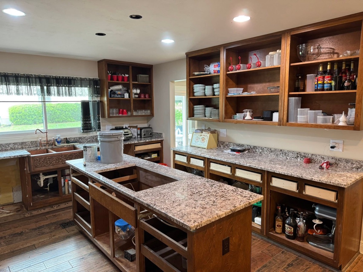 Kitchen mid-remodel with a granite island and unfinished custom pantry shelving