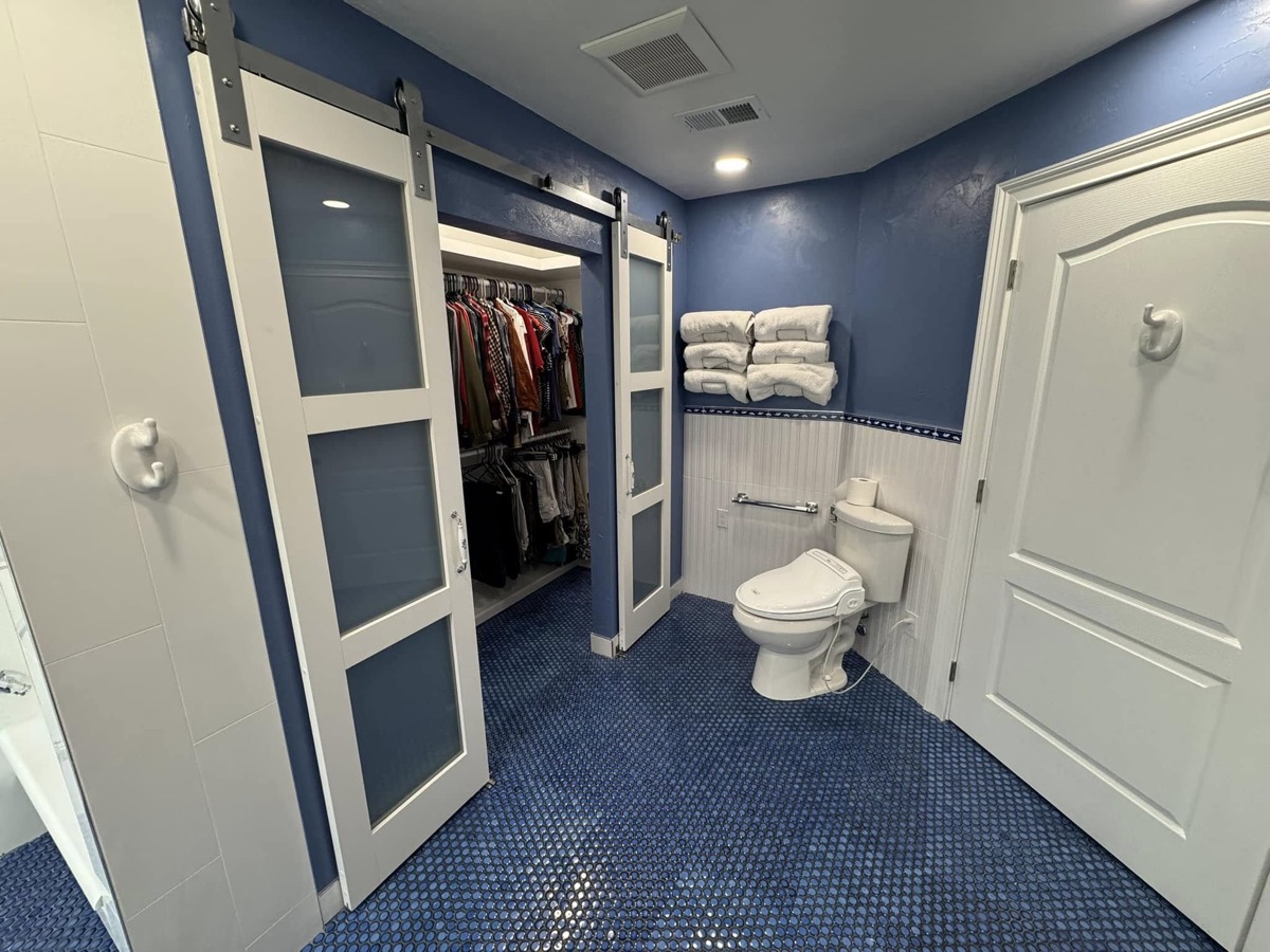 Finished bathroom with a sliding barn door closet, blue penny-tile floor and white fixtures