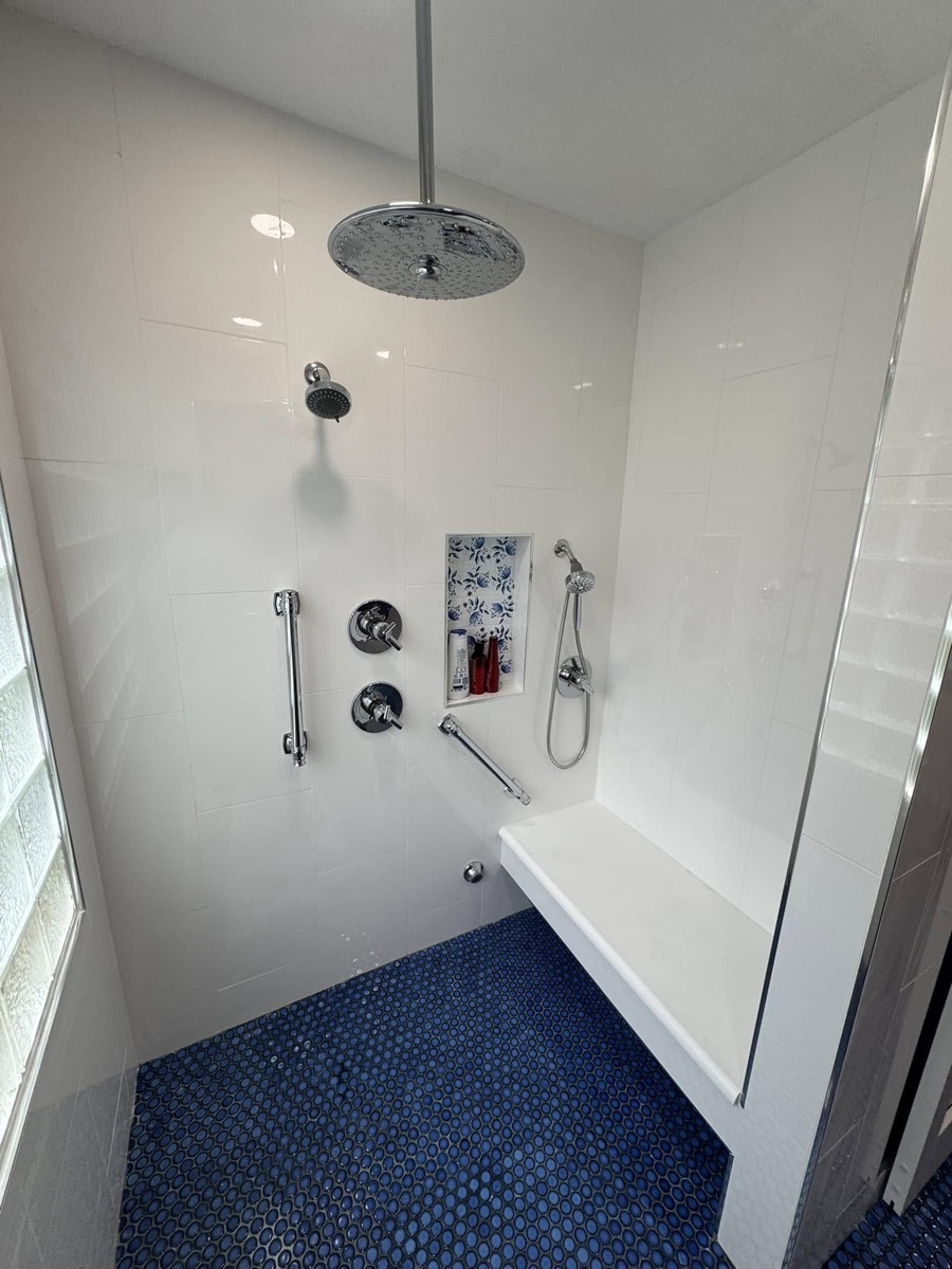 Finished white tile roll-in shower with rain head, hand shower, grab bar and bench