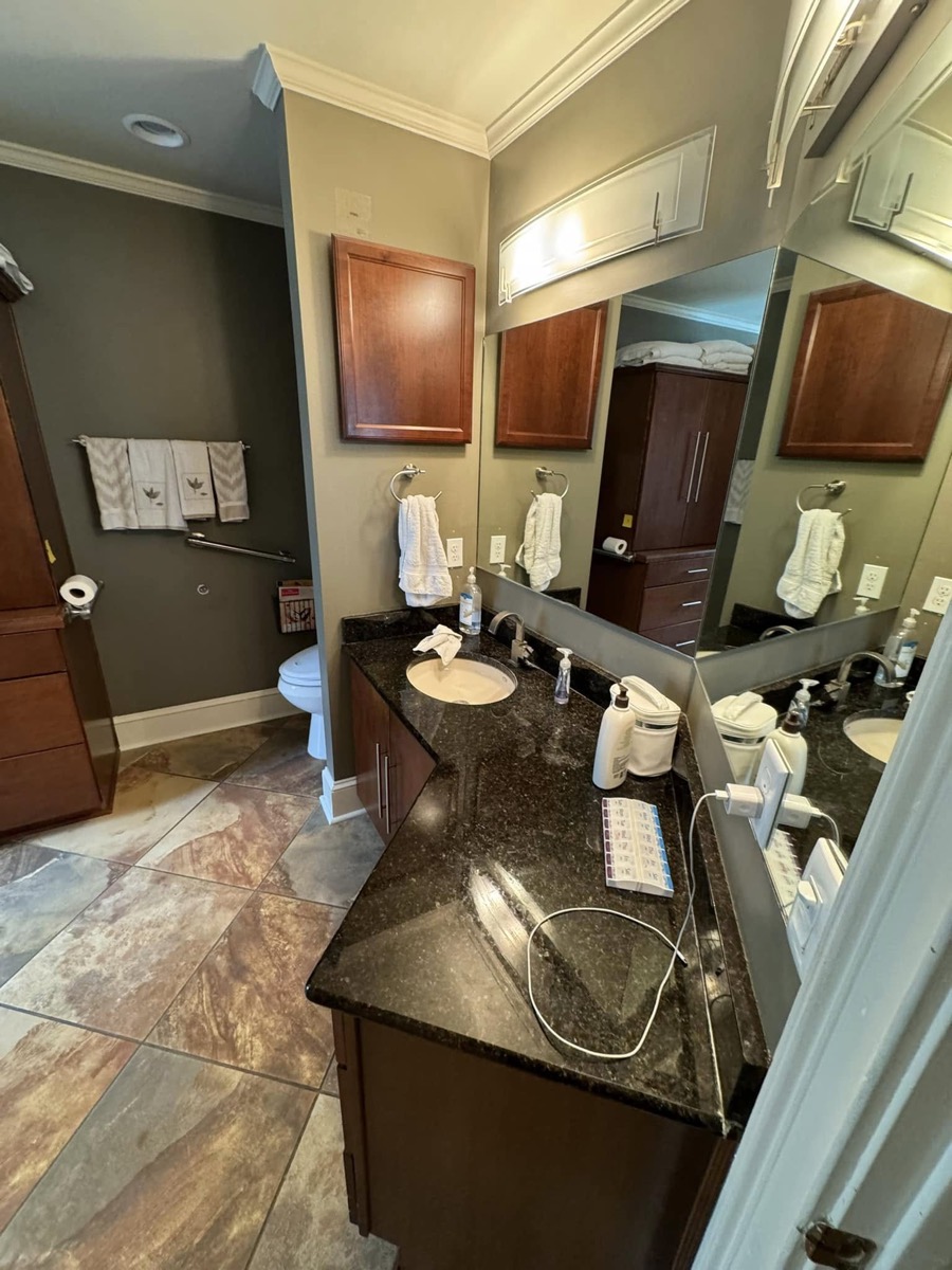 Old bathroom with slate tile floor, dark wood vanity with granite top and a glass block window